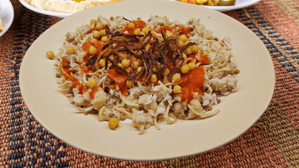 Koshary with rice, lentils, pasta, chickpeas, tomato sauce and fried onions.